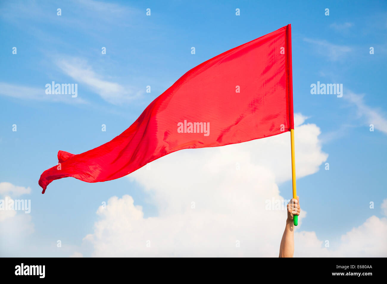 Hand winkend eine rote Fahne mit blauer Himmelshintergrund Stockfoto
