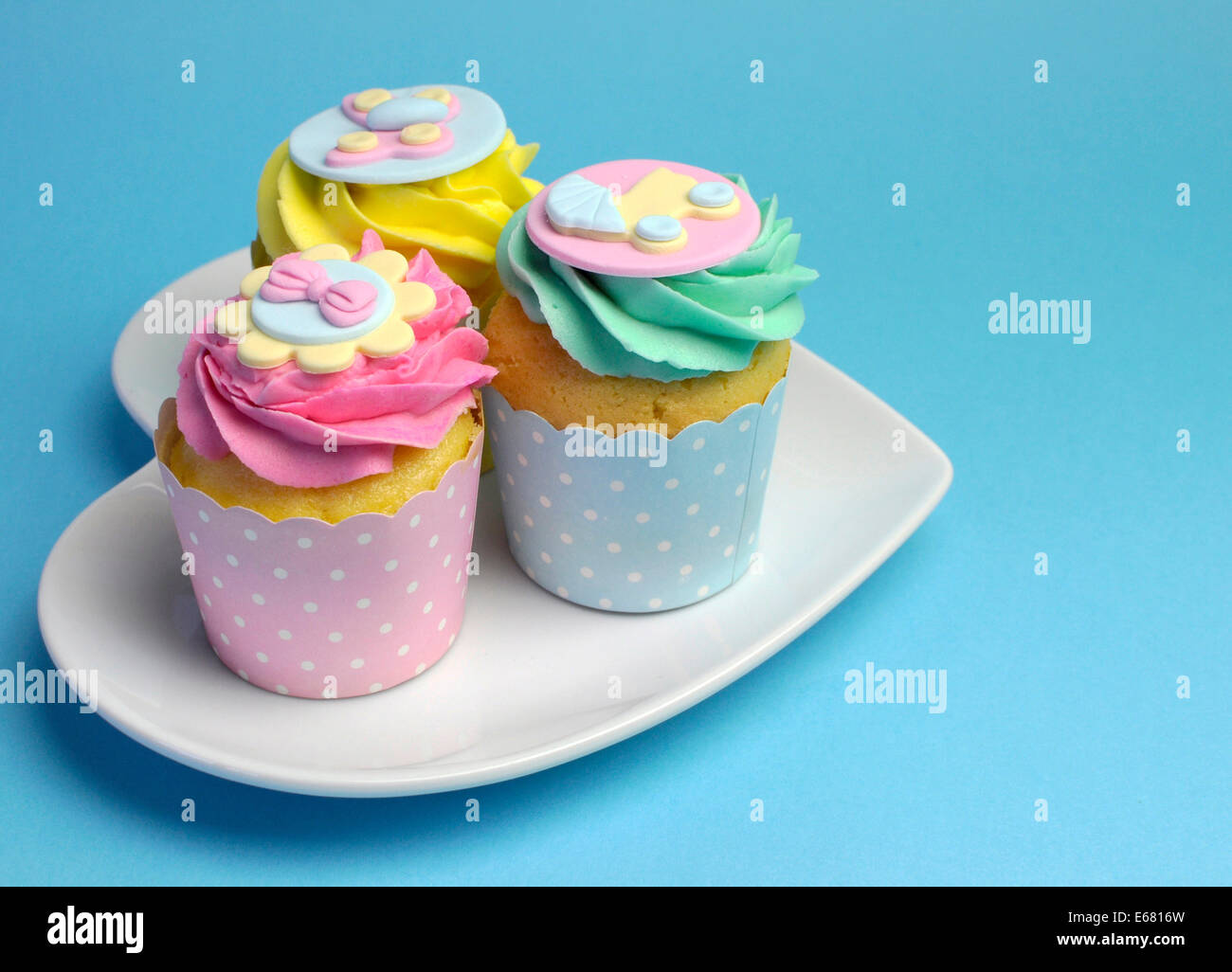 Schöne rosa, Aqua blau und gelb Cupcakes auf weißes Herz Form Platte für Baby-Dusche oder Kinder-party. Stockfoto