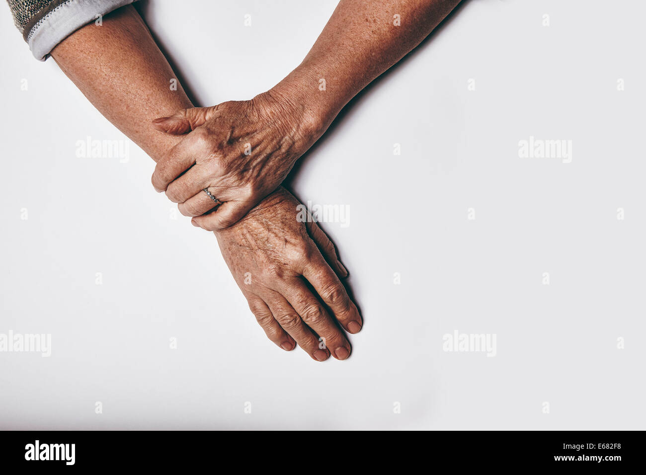Draufsicht auf eine ältere Frau Hände ruhen auf grauem Hintergrund. Entspannt, alte weibliche Hände zusammen. Stockfoto