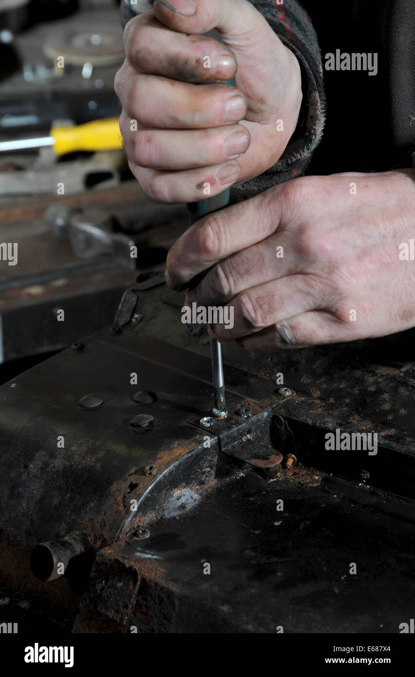 Mann mit Schraubenzieher auf Metall Autoteil Stockfoto