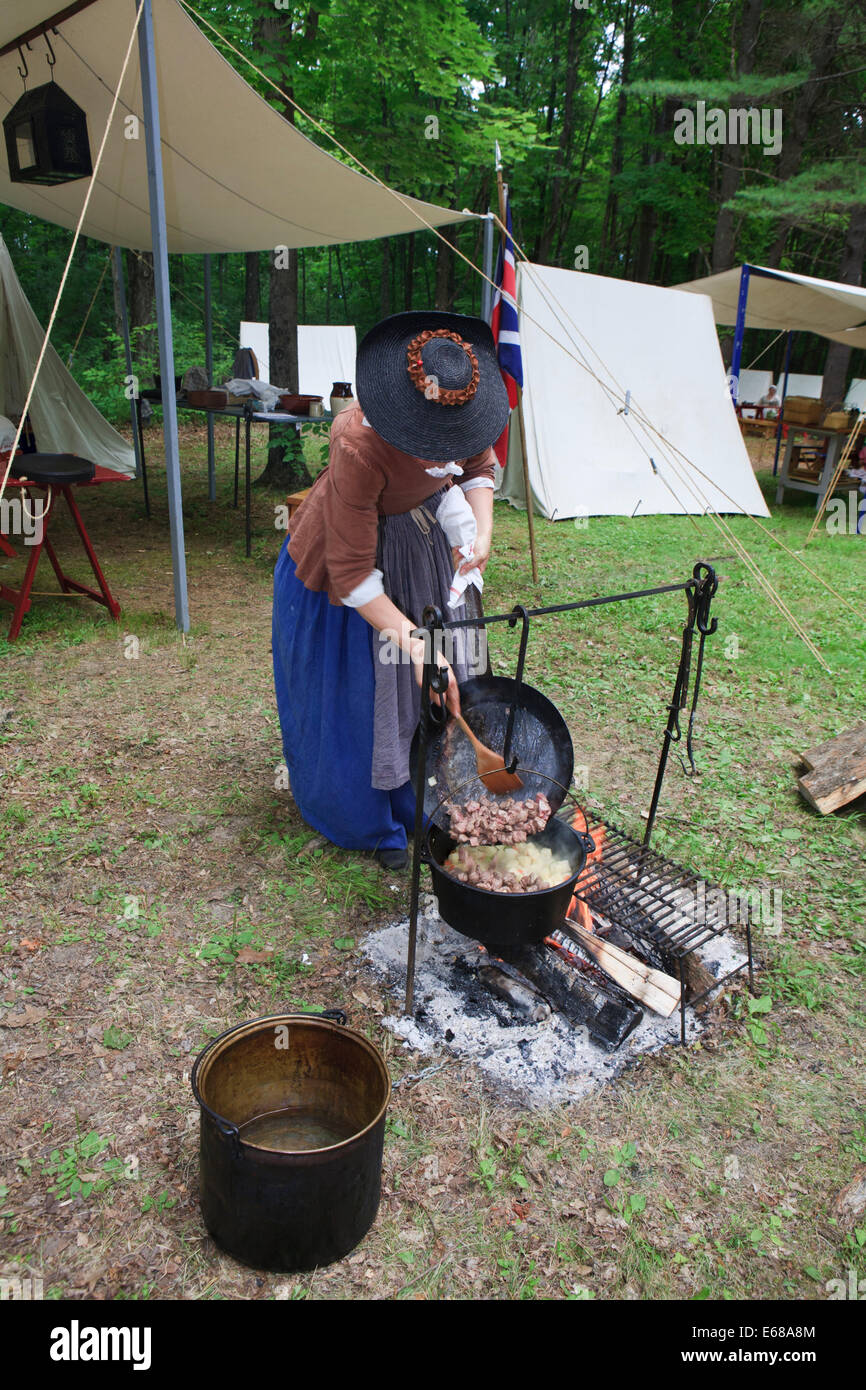 Frau kochen Abendessen über Lagerfeuer im amerikanischen revolutionären Krieg Reenactment Campingplatz Stockfoto