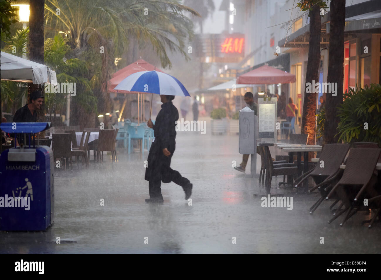 Kellner unter einem Regenschirm, die Öffentlichkeit im strömenden Regen zu dienen Stockfoto