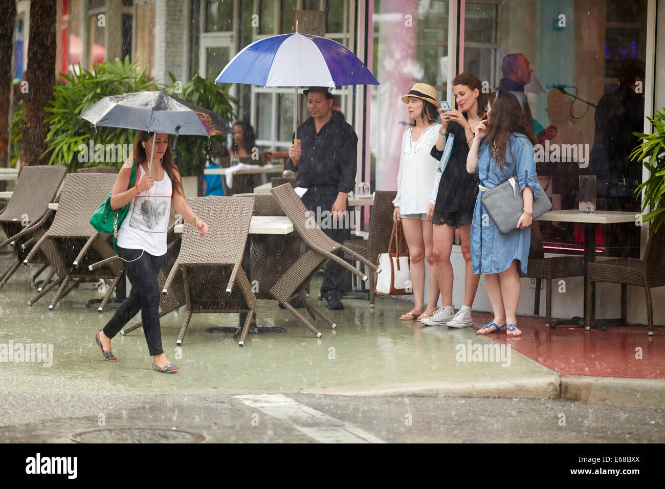 Tropischer Sturm bringt die Geschäfte und Restaurants zu einer stoppen, abgebildeten jungen Dame zu Fuß in den Regen als andere Tierheim Stockfoto