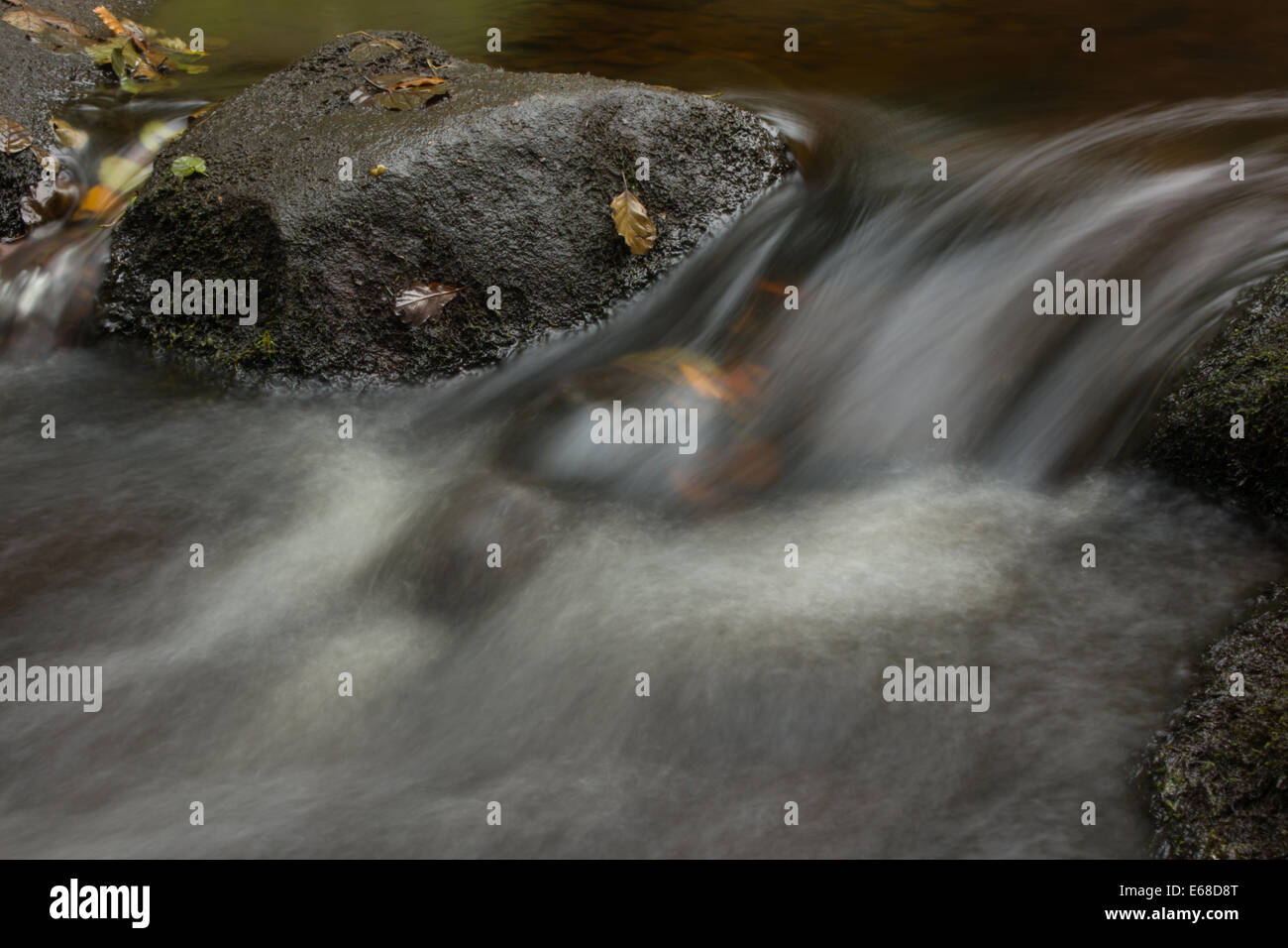 Ein Bild von einem stream Kaskadierung über blattsänfte zwischen einem Felsen. Eine langsamere Verschlusszeit ist gemildert das Aussehen des Wasser. Stockfoto