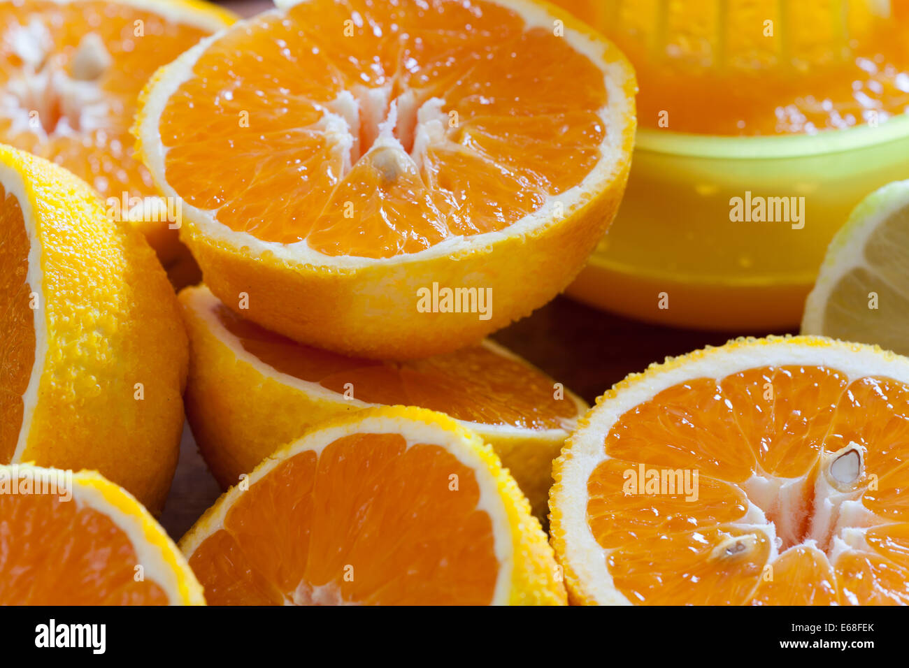 Saftige halbierte Orangen und eine Saftpresse im Hintergrund als Nahaufnahme Stockfoto