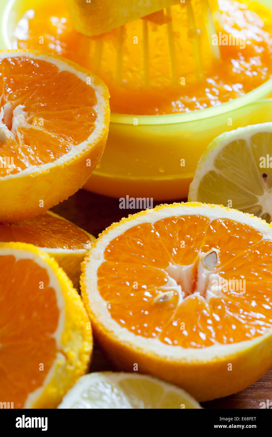 Saftige halbierte Orangen und eine Saftpresse im Hintergrund als Nahaufnahme Stockfoto