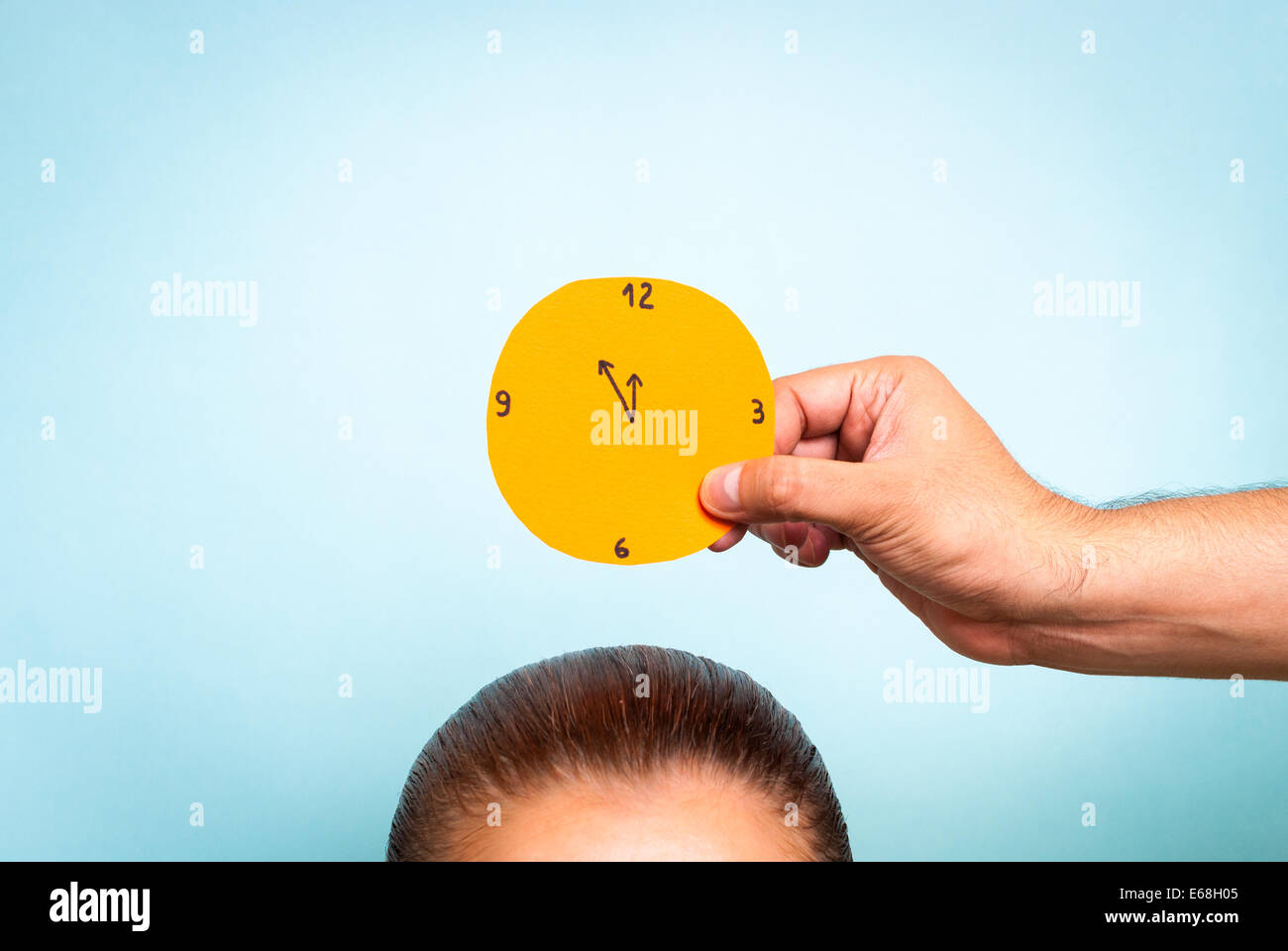 Tagesplanung. Orange clock über Frau auf blauem Hintergrund Stockfoto