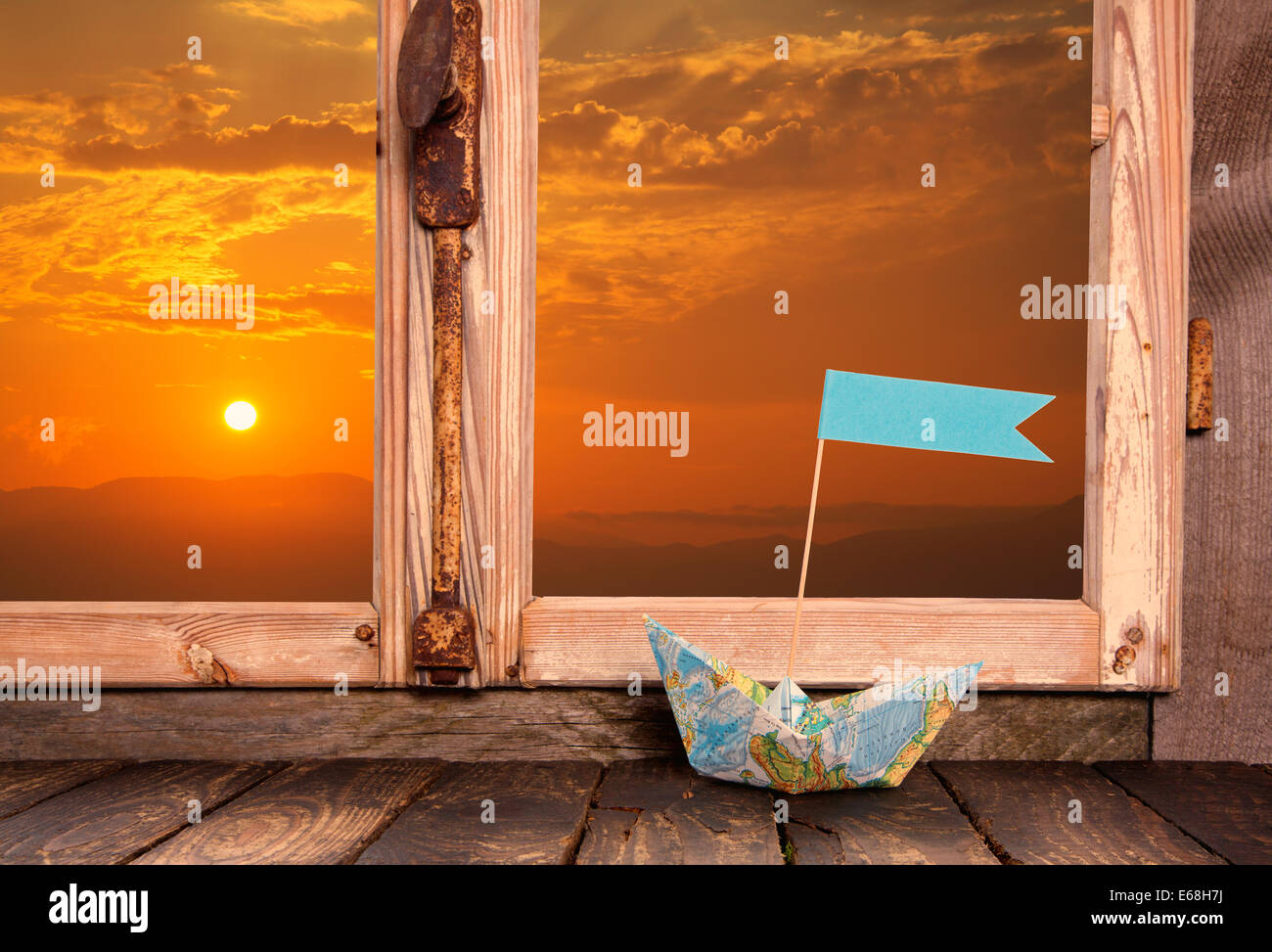 Urlaub Träume: Holzfenster Hintergrund mit Blick auf den Sonnenuntergang verziert mit einem Segelboot auf der Fensterbank. Stockfoto