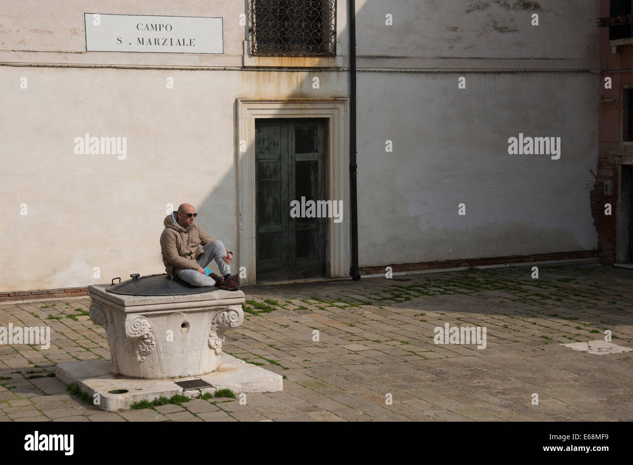 Mann sitzt Don die überdachte gut und blickt auf die verlassene Campo San Marziale in Venedig. Stockfoto