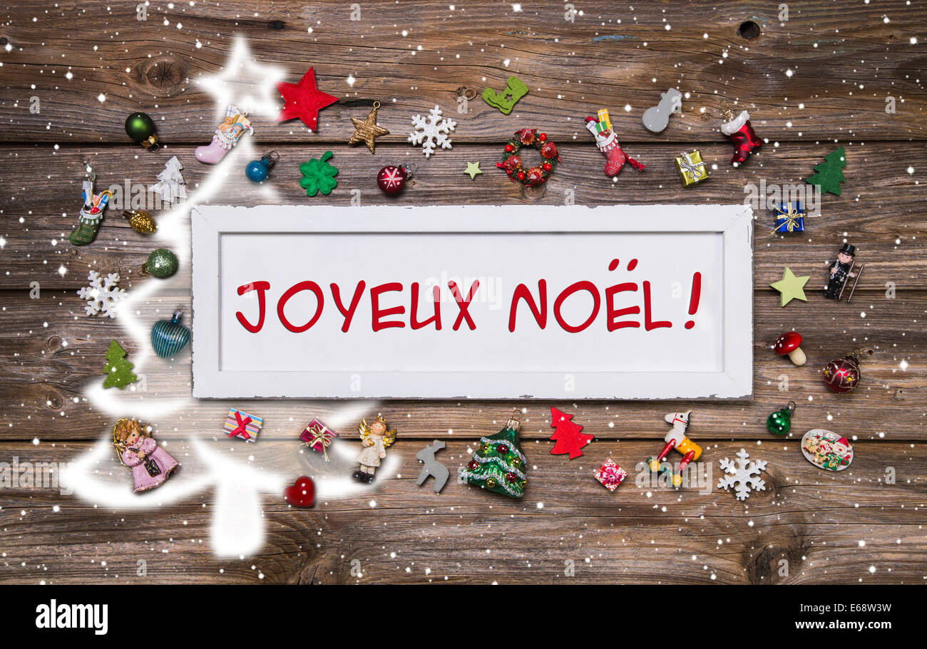 Frohe Weihnachten Grusskarte mit französischer Text - Dekoration bunt mit Miniaturen auf hölzernen Hintergrund mit Zeichen. Stockfoto