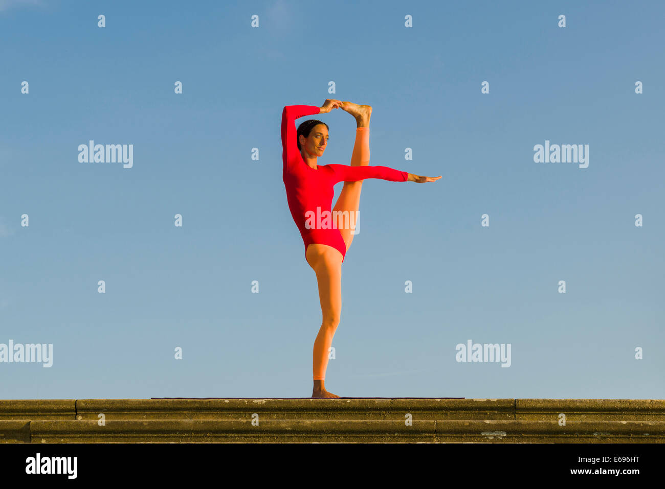 Junge Frau praktizieren Hatha Yoga im Freien, zeigen die Pose Utthita Hasta Pandangusthasana, hob die Hand zur Großzehe-pose Stockfoto