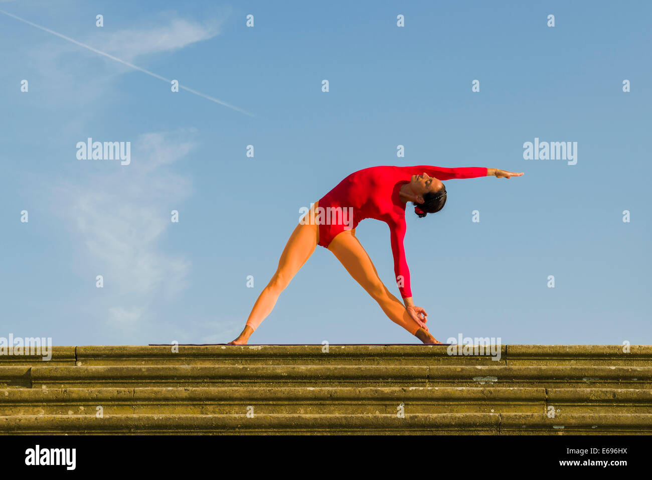 Junge Frau Hatha Yoga im Freien praktizieren, zeigt die Pose Trikonasana, Dreieck Stockfoto