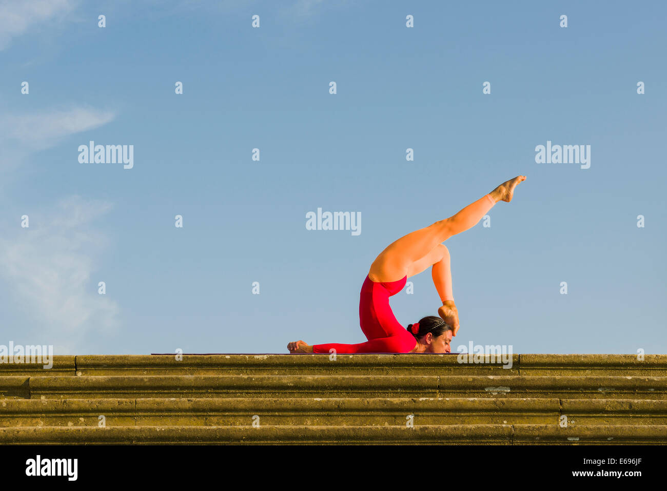 Junge Frau Hatha Yoga im Freien praktizieren, zeigt die Pose Shalabhasana, Heuschrecke Stockfoto