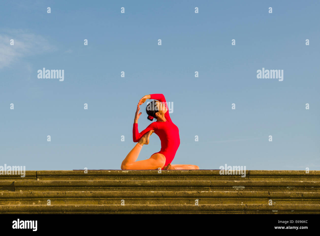 Junge Frau Hatha Yoga im Freien praktizieren, zeigt die Pose Kapotasana, Pigeon pose Stockfoto