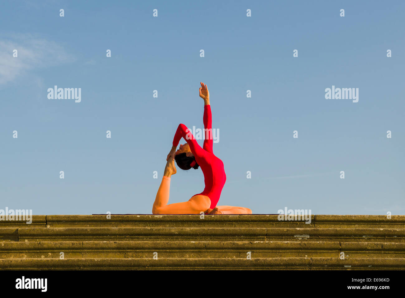 Junge Frau Hatha Yoga im Freien praktizieren, zeigt die Pose Kapotasana, Pigeon pose Stockfoto