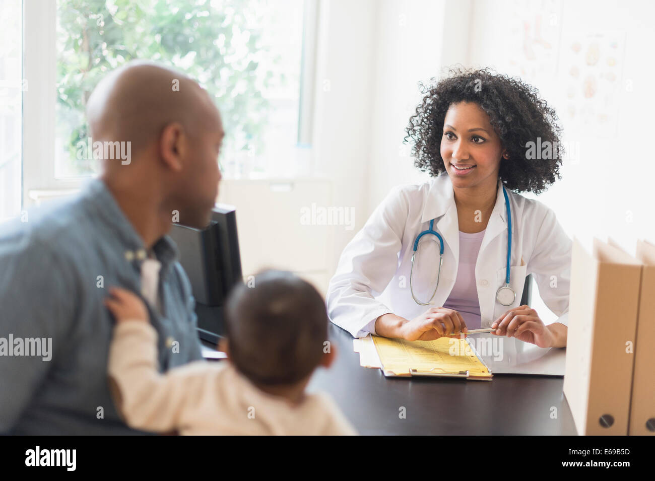 Vater mit Baby Rücksprache mit Arzt Stockfoto