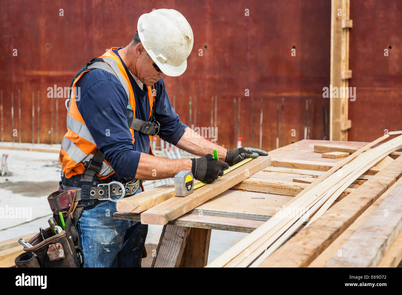 Kaukasische Arbeiter messen Holz auf Baustelle Stockfoto