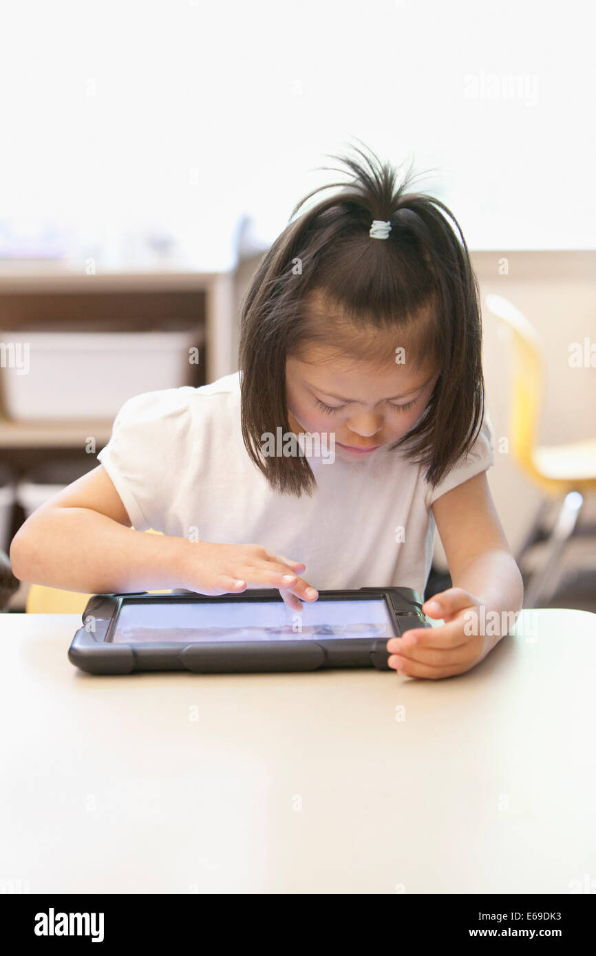Gemischte Rassen Down Syndrom Student mit Tablet-Computer im Klassenzimmer Stockfoto
