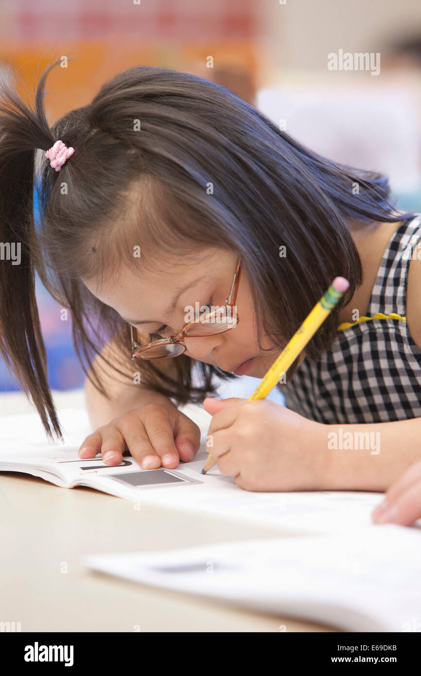 Gemischte Rassen Down Syndrom Schüler schreiben in Arbeitsmappe Stockfoto