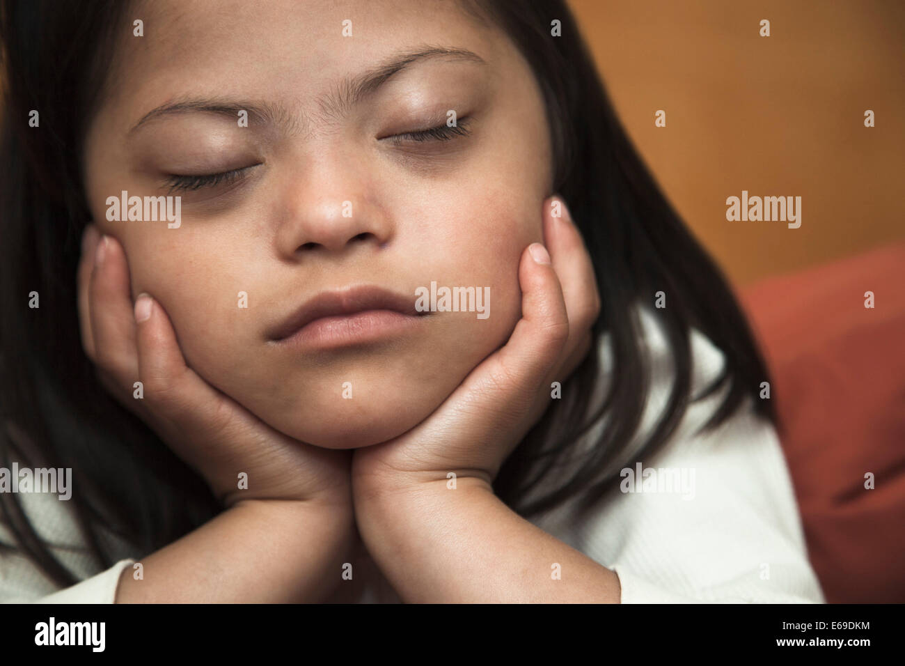 Gemischte Rassen Down Syndrom Mädchen mit Kinn in Händen ruhen Stockfoto