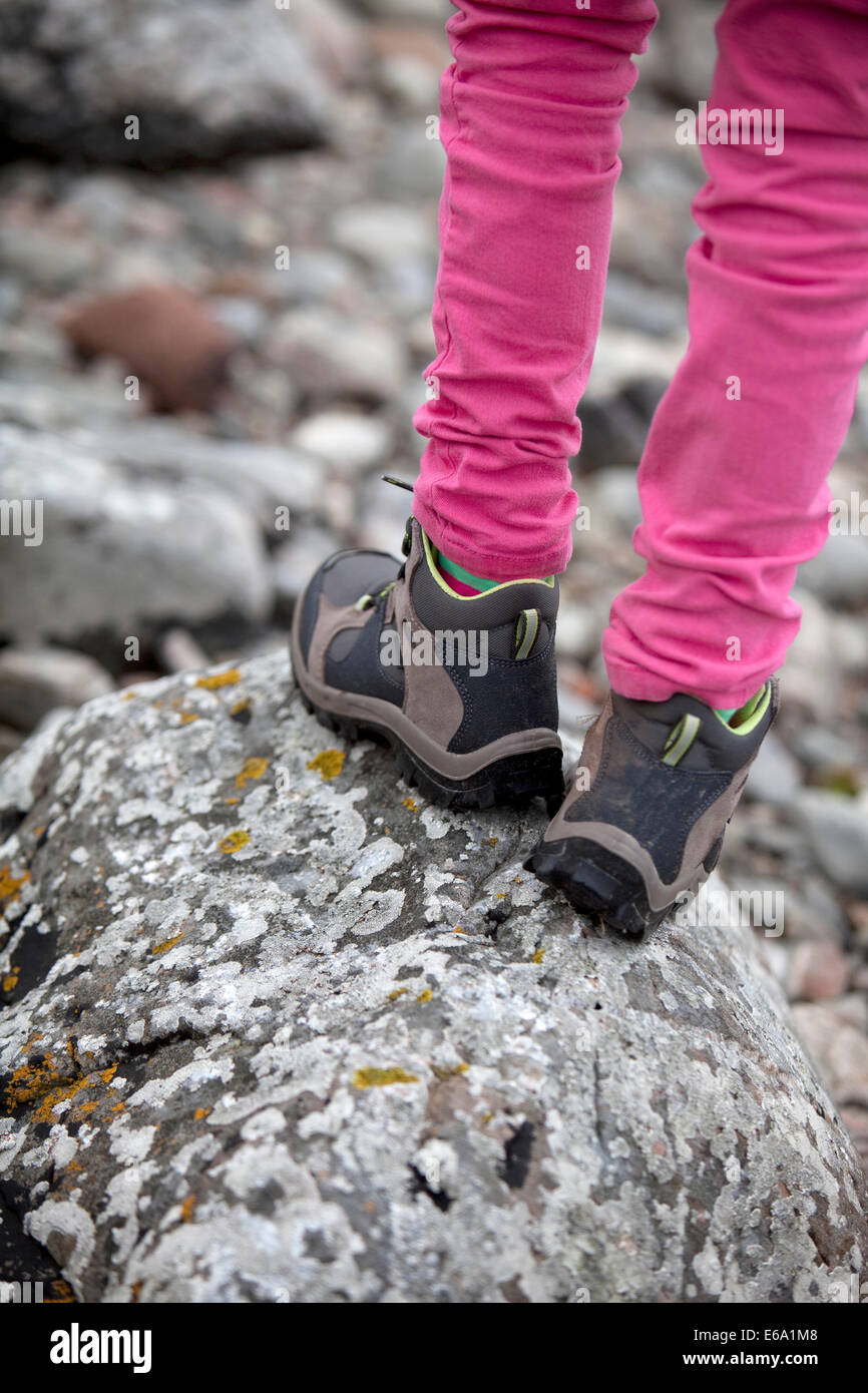 Kind tragen Stiefel und steht auf einem Flechten bedeckten Felsen auf einen Küstenweg in Schottland. Stockfoto