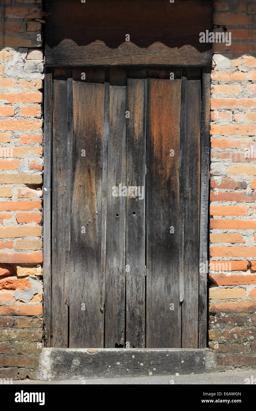 Eine verwitterte Holztür in einer Mauer aus Lehmziegeln in Cotacachi, Ecuador Stockfoto