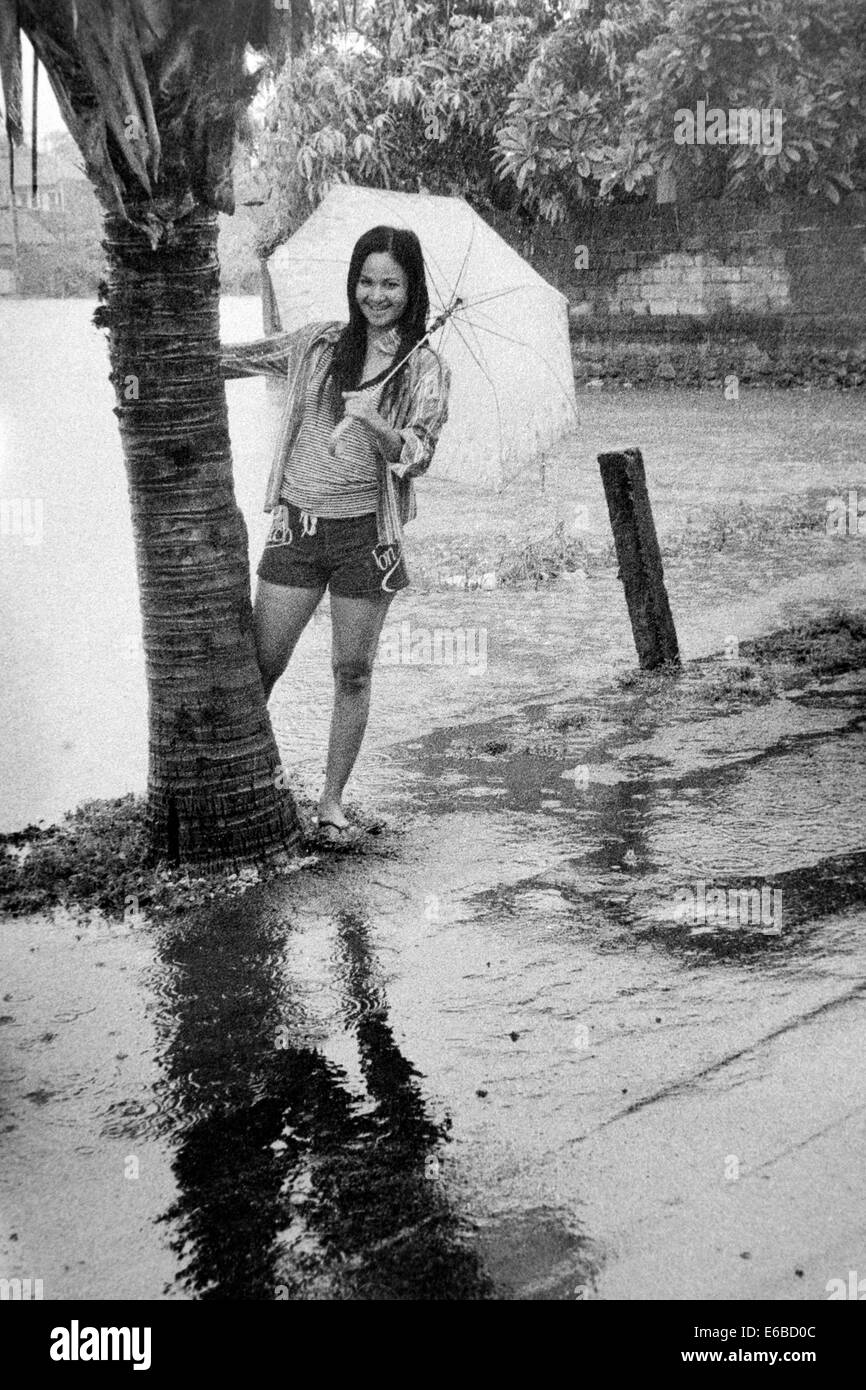 junge Frau mit Regenschirm Starkregen zu genießen, während ein Monsun-Regen in Bali Indonesien Stockfoto