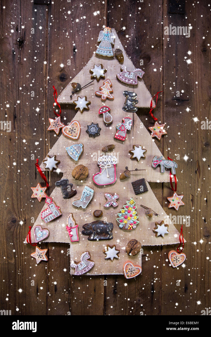 Handgemachte geschnitzte Weihnachtsbaum dekoriert mit Lebkuchen, Sternen und Herzen auf hölzernen Hintergrund. Stockfoto