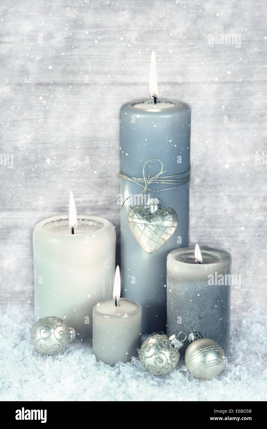 Vier blauen, grauen und weißen brennenden Advent Kerzen mit Schnee im shabby chic Stil. Stockfoto