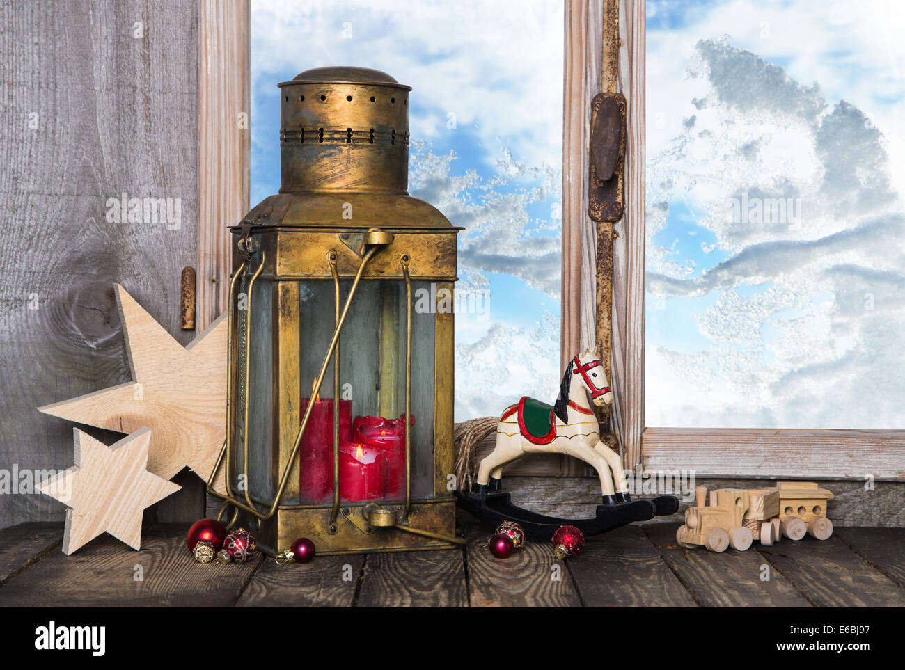 Nostalgische alte Weihnachts-Dekoration mit alten Spielsachen und eine alte Laterne mit Kerzen auf der Fensterbank. Stockfoto