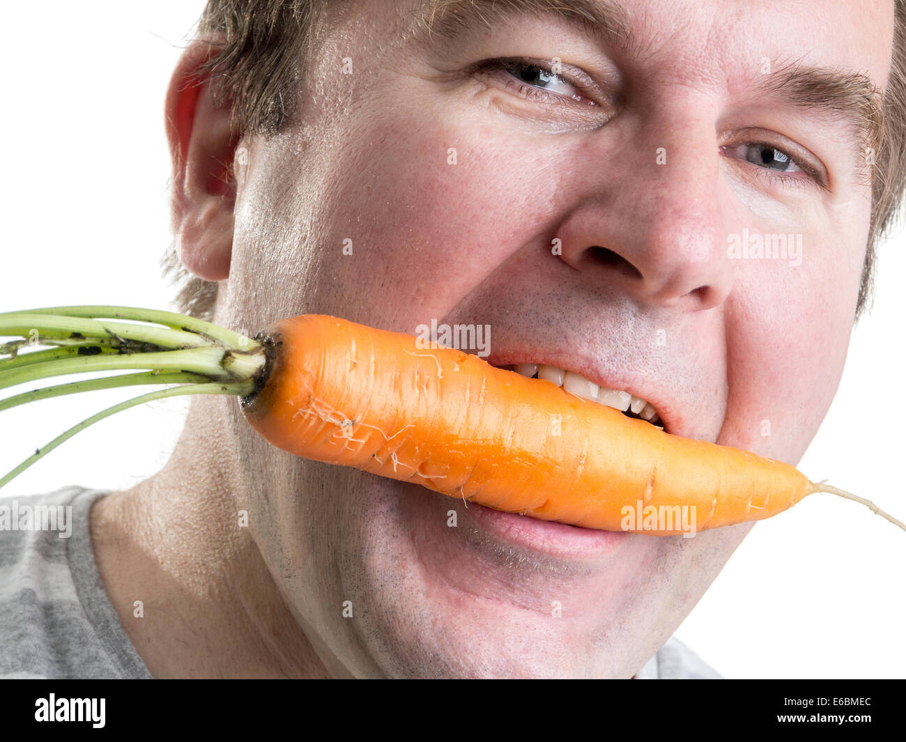 Mann, der eine frische Möhre in den Mund hält Stockfoto