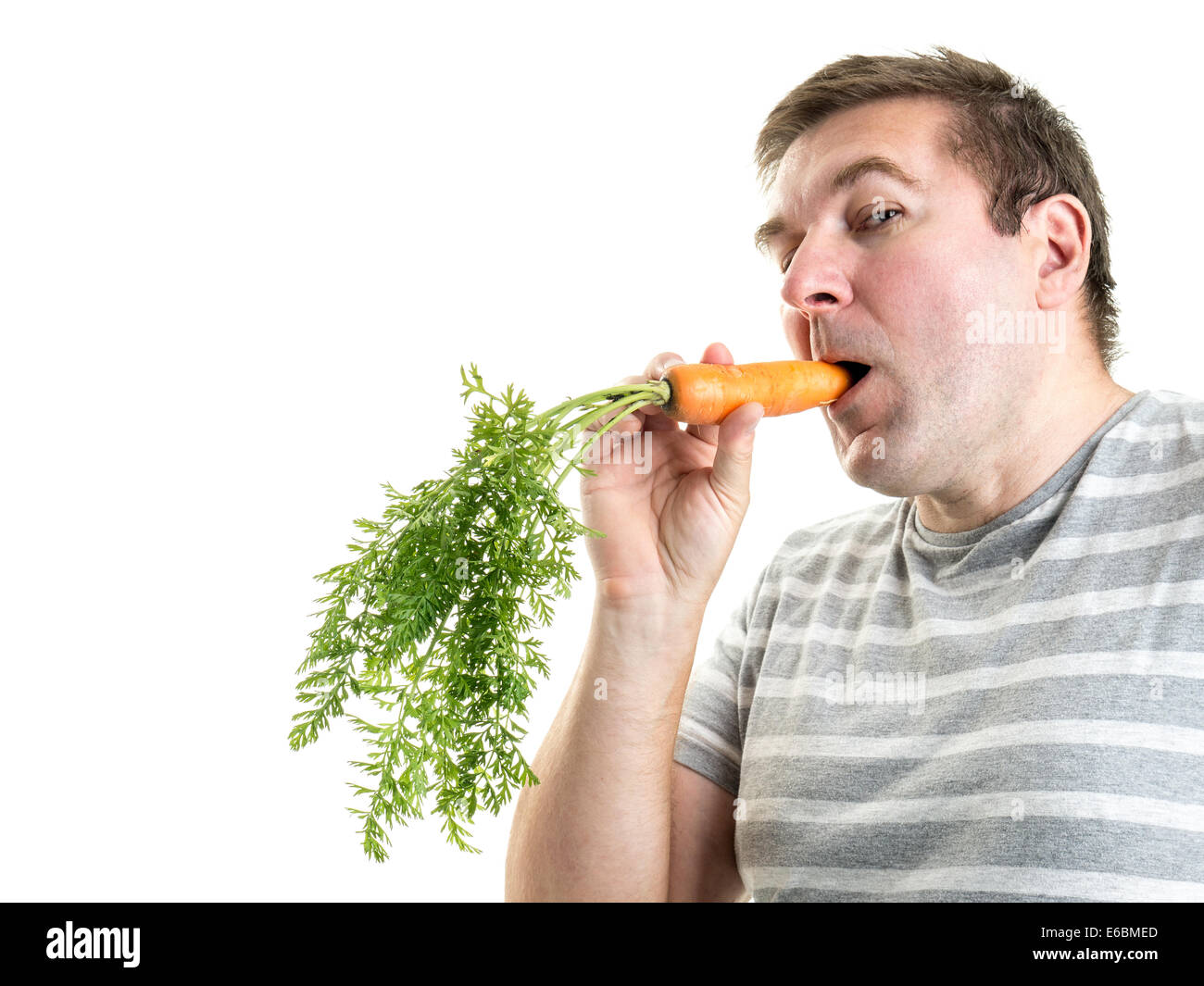 Mann, der eine frische Möhre in den Mund hält Stockfoto