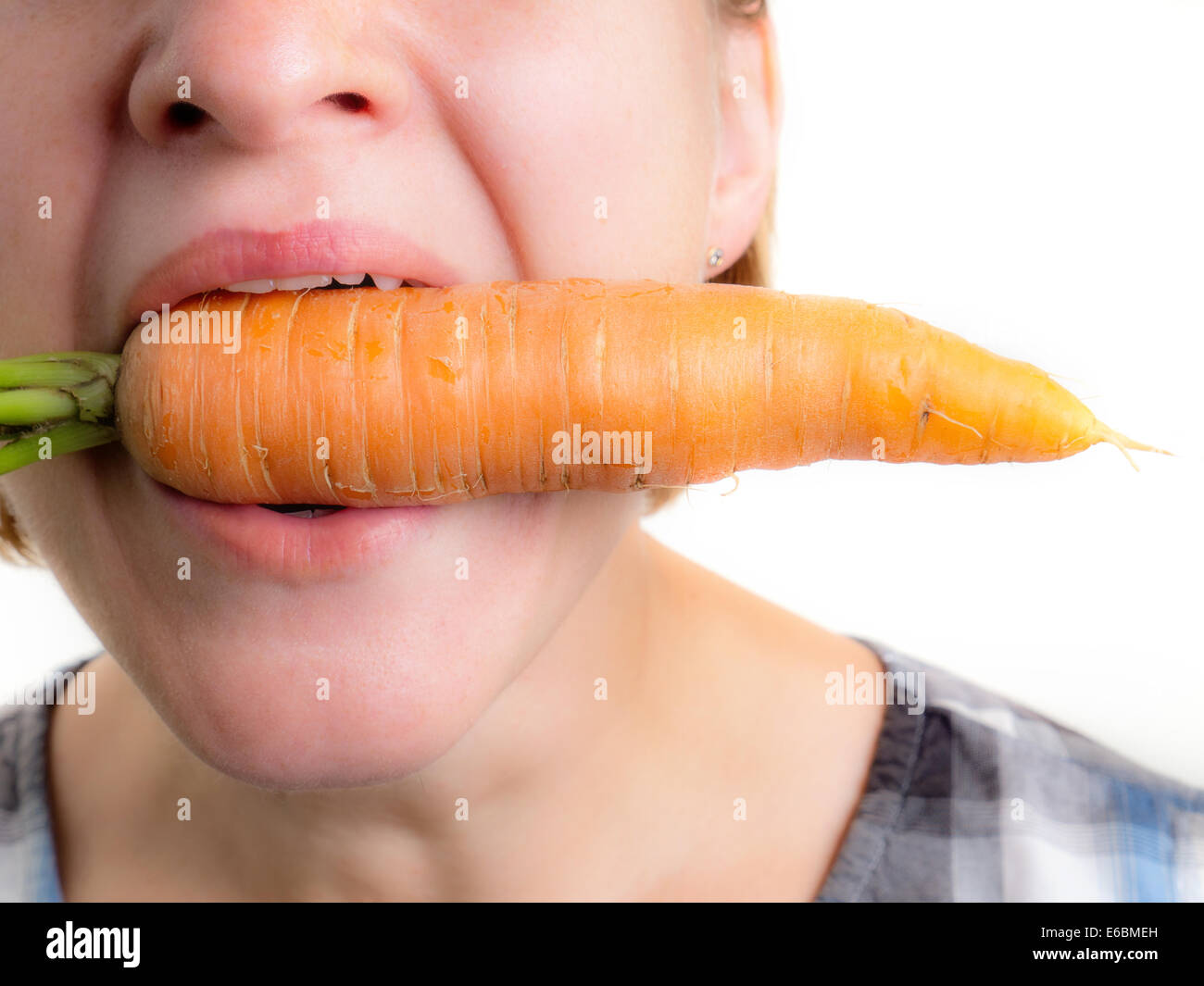 Frau hält eine frische Möhre in den Mund Stockfoto