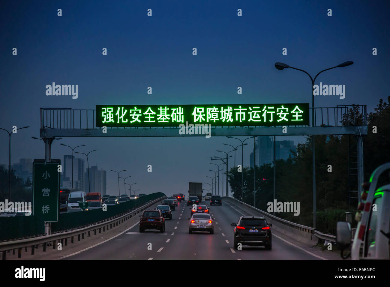 Verkehr auf einer Autobahn bei Einbruch der Dunkelheit beleuchtet mit einem chinesischen Banner, Peking, China Stockfoto