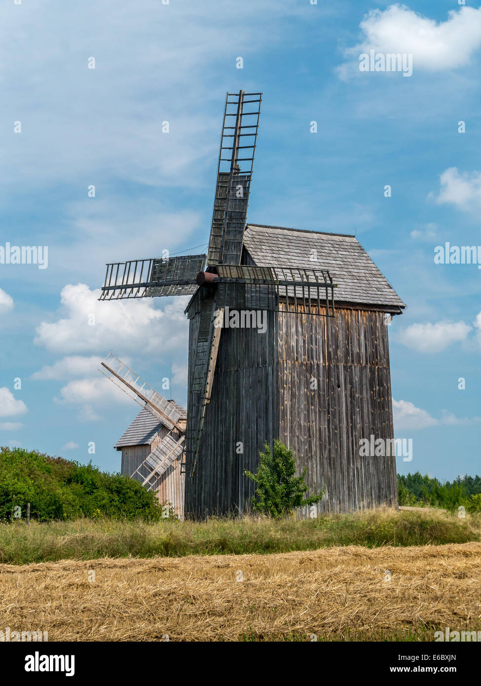 Zwei alte hölzerne Windmühlen gegen blauen Himmel Stockfoto