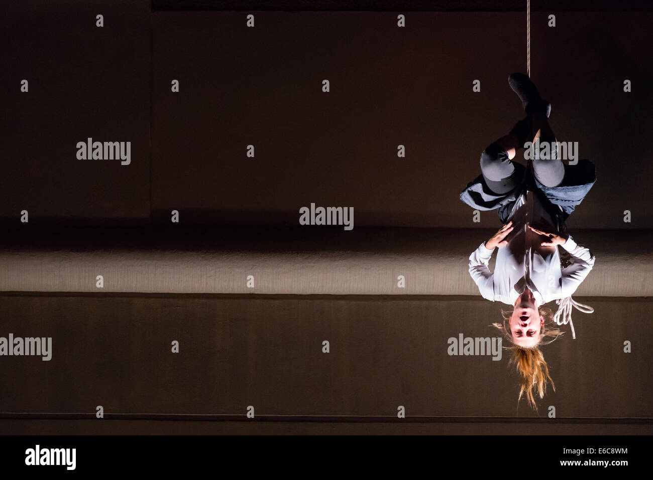 Frau kopfüber hängend an einer Schnur, Szene aus Vertigo - vertikale Tanz mit multimedia, Straße Theatershow Stockfoto