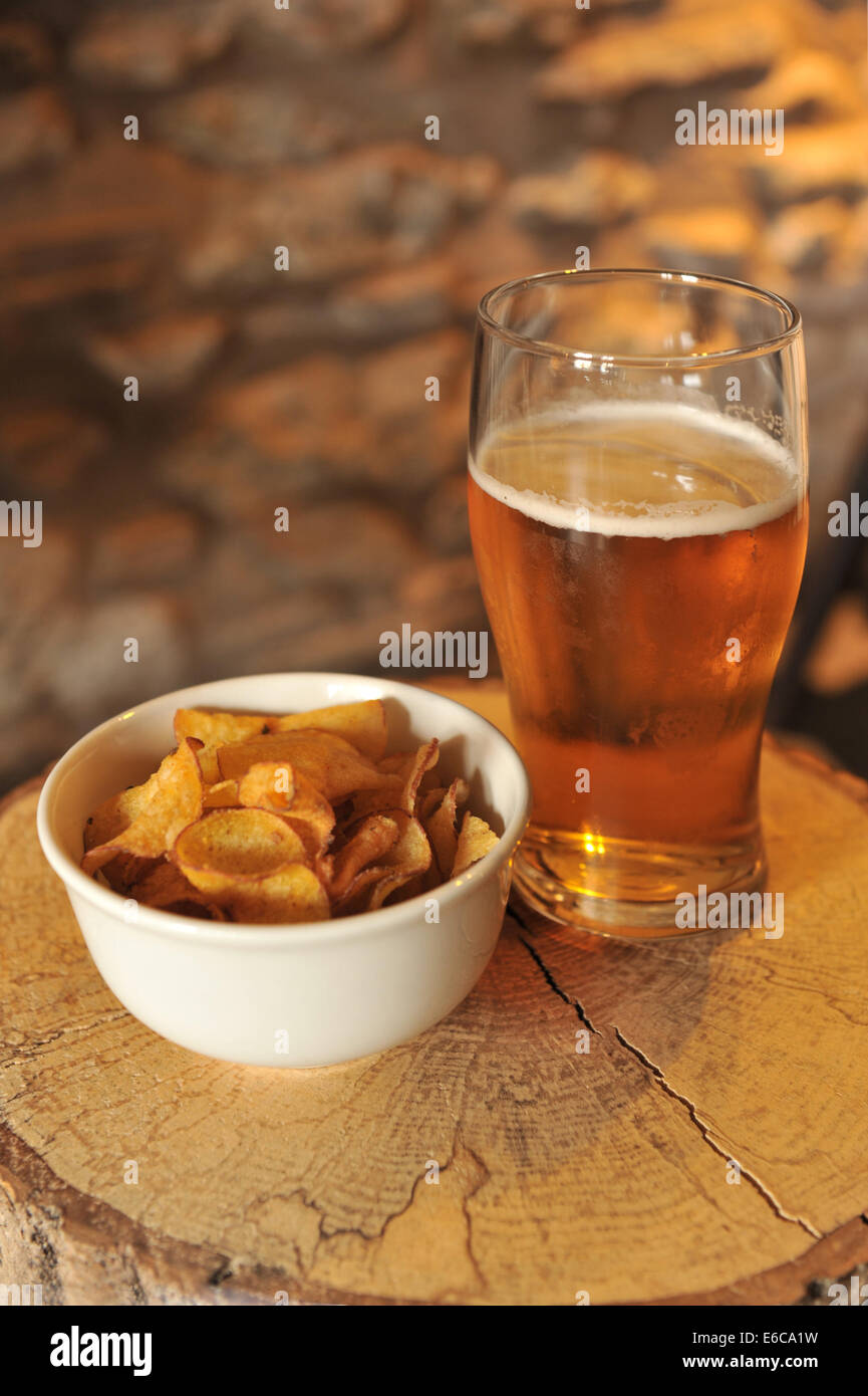 Kettle Chips in einer Schüssel neben ein real Ale auf einem rustikalen melden Sie sich an ein traditionelles englisches Pub, The Kilpeck Inn, Herefordshire. Stockfoto