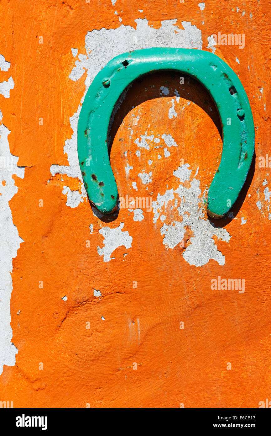 Grüne Hufeisen dekorieren eine Peeling orange Wand, Frankreich, Europa Stockfoto
