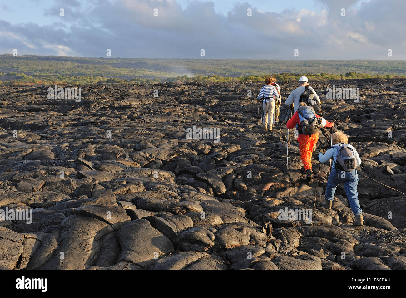 Gruppe der Wanderer Wandern an gekühlten Pahoehoe-lava flow bei Sonnenaufgang, Kilauea, Big Island, Hawaii Volcanoes National Park, USA Stockfoto