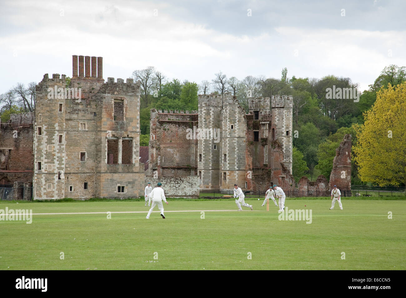Ein Cricket-Spiel gespielt wird im Cowdray Park in Sussex England UK, mit einem Hintergrund von Cowdray House, eine Tudor Ruine. Stockfoto
