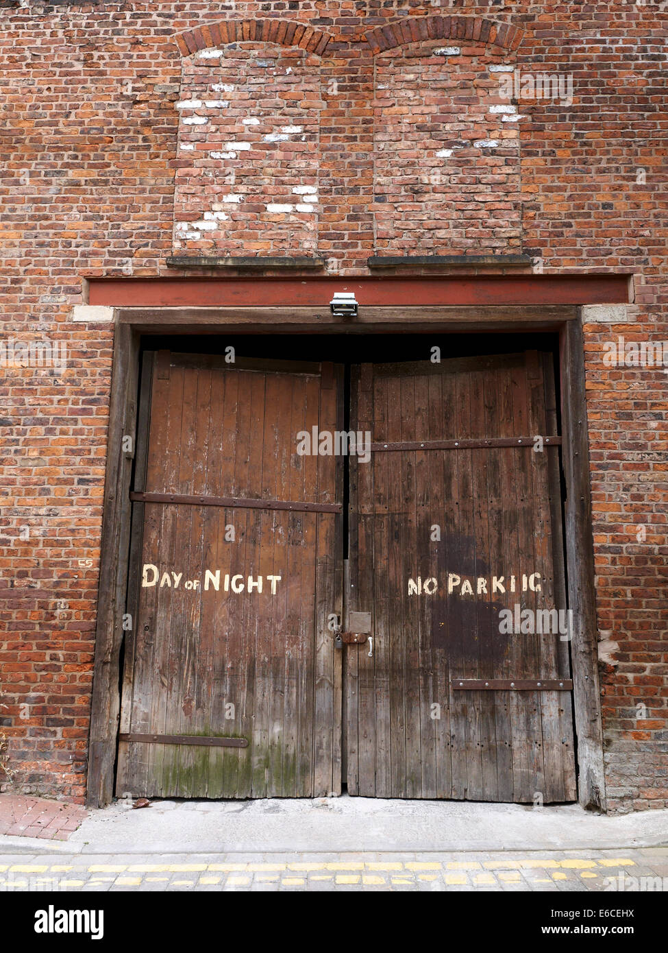Kein Parkplatz Tages-und Nachtzeit gemalt auf alten Industrietor mit blockierten Fenster in Manchester UK Stockfoto