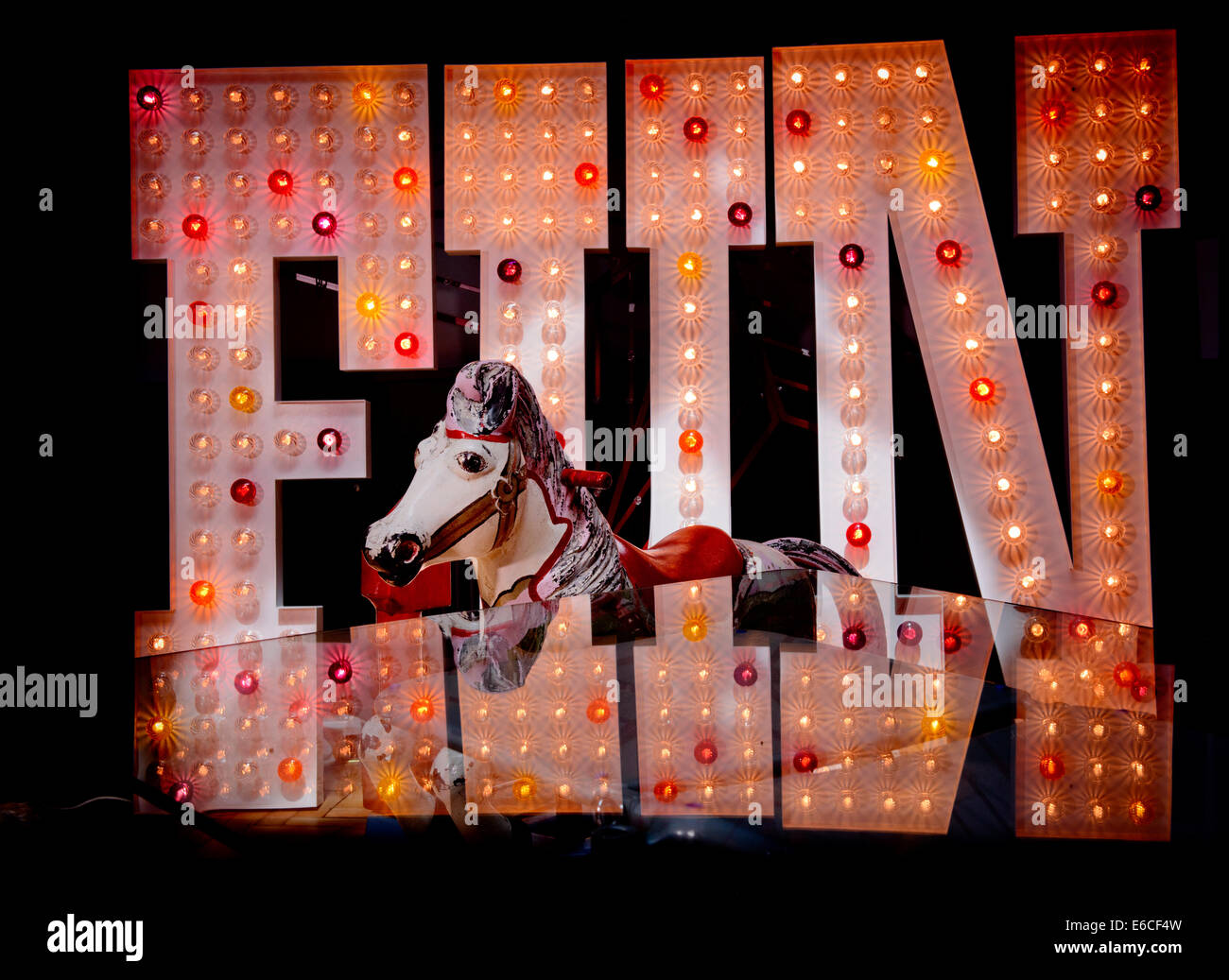 Eine große beleuchtete Messegelände Zeichen das Wort Spaß und ein Pferd von einem Karussell in East Sussex UK. Stockfoto