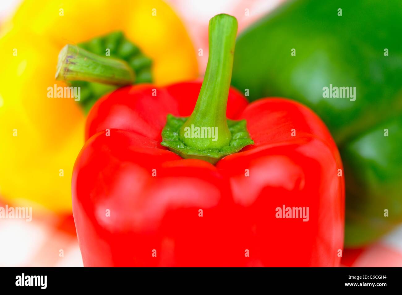 Gelbe und grüne Paprika auf rot karierte Tischdecke Hintergrund Stockfoto
