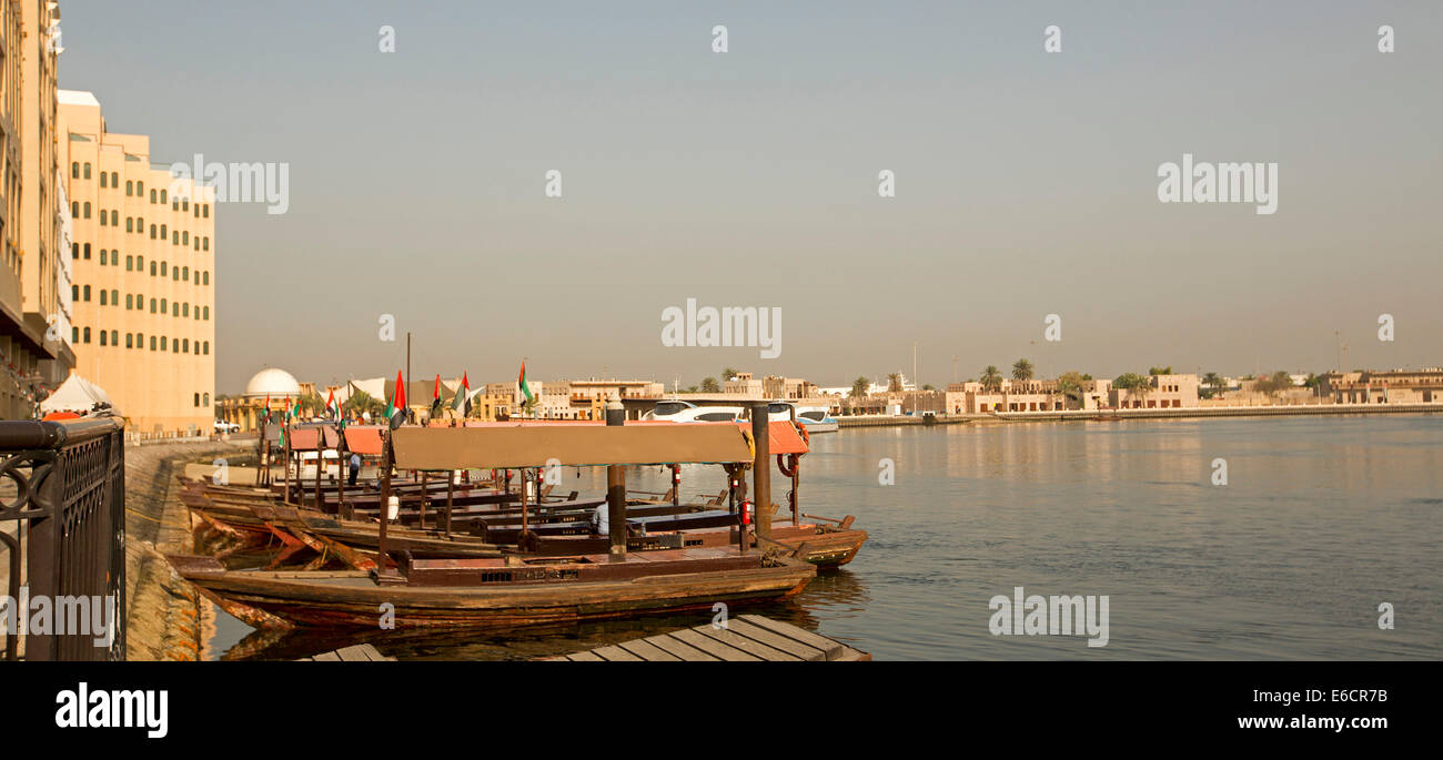 Holzboote, traditionelle Abras als kleine ÖPNV Fähren am Dubai Creek mit Gebäuden im Hintergrund in der Stadt Dubai Stockfoto