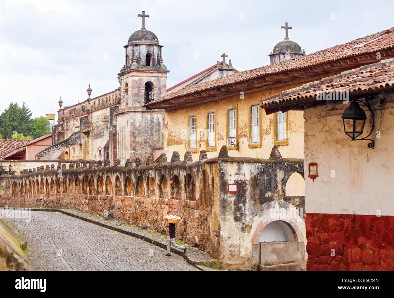 Ein Junge, ein Brot Korb auf dem Kopf überquert die Straße in Patzcuaro, Michoacan, Mexiko. Stockfoto