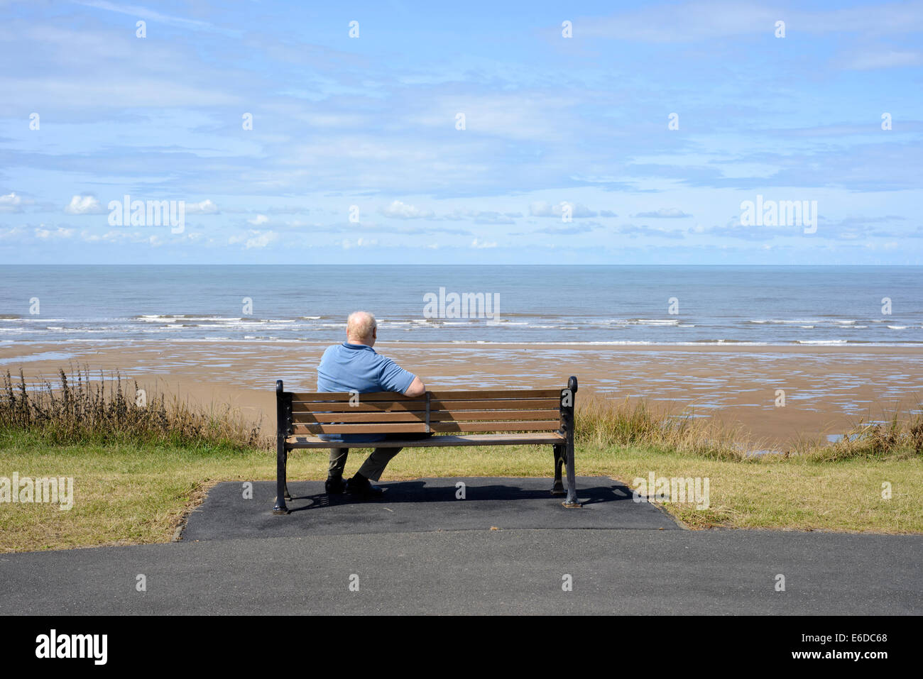 Einsame ältere Mann sitzt auf Holzbank mit Blick aufs Meer in Blackpool, Lancashire. Stockfoto