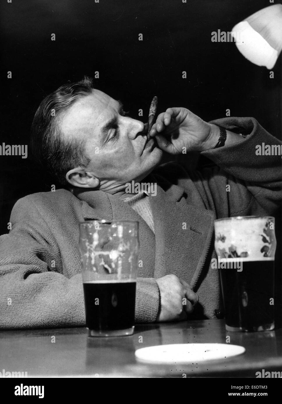 London, UK, UK. 15. Dezember 1951. (Datum/Ort unbekannt) Buchmacher J. STORR hält seine Asche hoch, wie er seine Zigarre mit ein paar Pints Bier genießt. © KEYSTONE Pictures/ZUMAPRESS.com/Alamy Live-Nachrichten Stockfoto