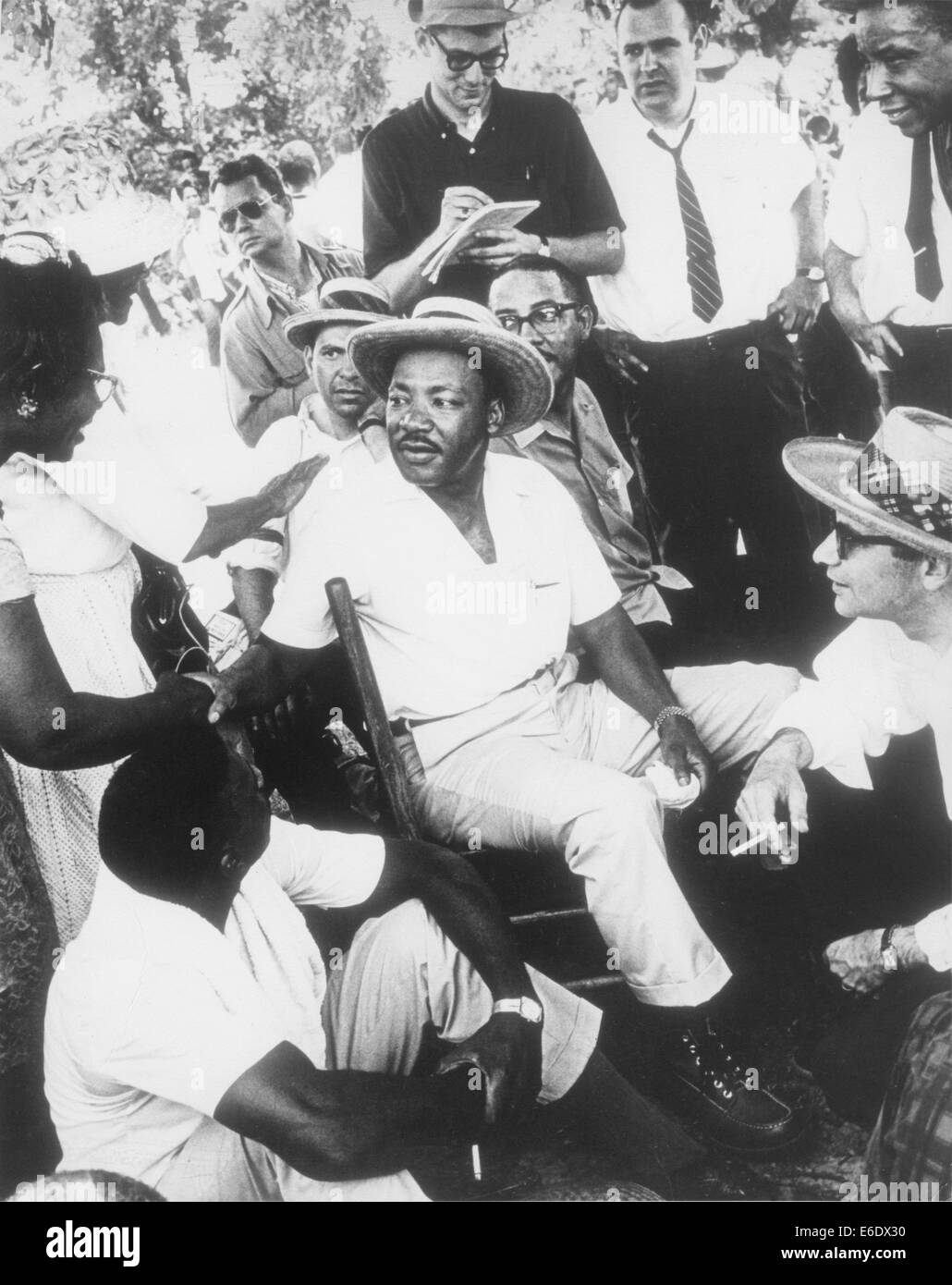 Martin Luther King, Jr. in Strohhut, setzen Sie sich mit einer Gruppe von Männern beim Händeschütteln mit Frau, ca. 1960 Stockfoto