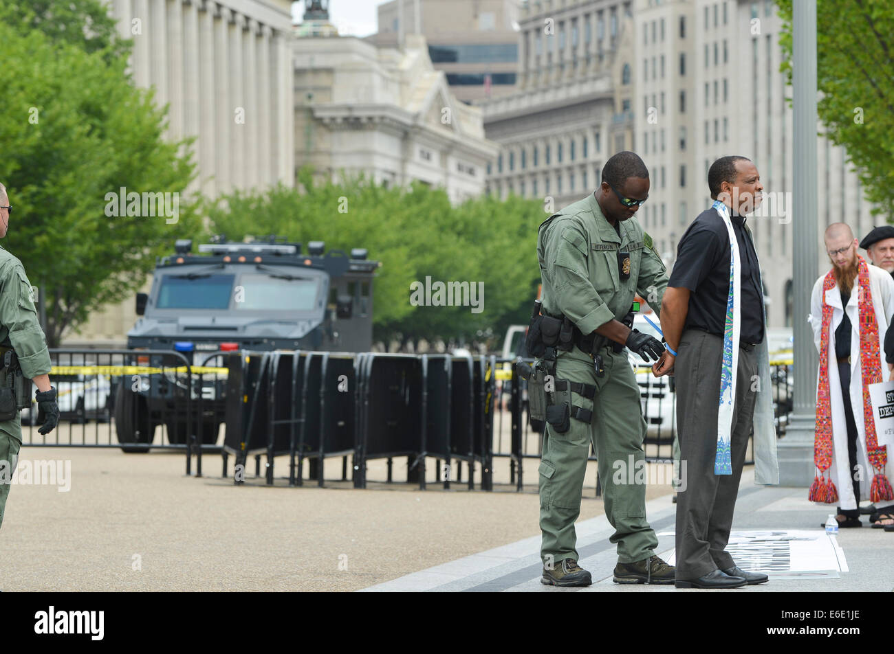 Washington, DC, USA. 31. Juli 2014. Ein Mitglied des Klerus ist vor dem weißen Haus während einer Einwanderung Protest festgenommen, die glauben Führungskräfte aus der Evangelisch-methodistischen Kirche, Katholiken, unitarischen Universalisten, Quäker, Juden und andere enthalten. Obwohl die Glaubens-Führer mit US Park Police kooperiert und benachrichtigt sie im Vorfeld der friedlichen Protest und ihre Absicht, verhaftet zu werden, die Antwort der Polizei enthalten eine Militär-Stil "BearCat" gepanzerte Mannschaftswagen, im Hintergrund zu sehen. Polizei-Einsatz solcher Geräte in Ferguson, Missouri, und anderen Orten hat brough Stockfoto