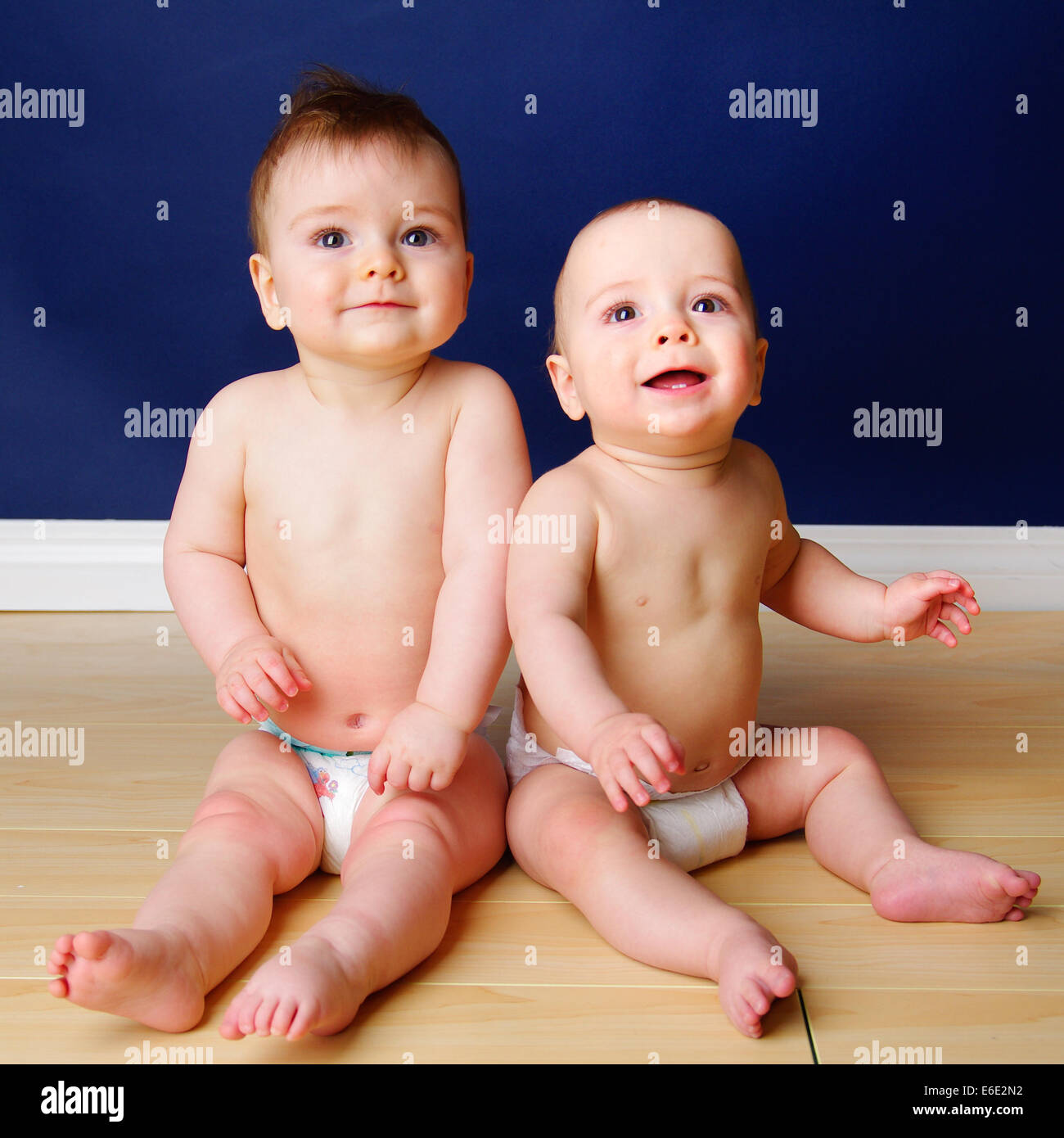 Zwillingsbruder 9 Monate altes Baby jungen sitzen nebeneinander in ihren  Windeln Stockfotografie - Alamy